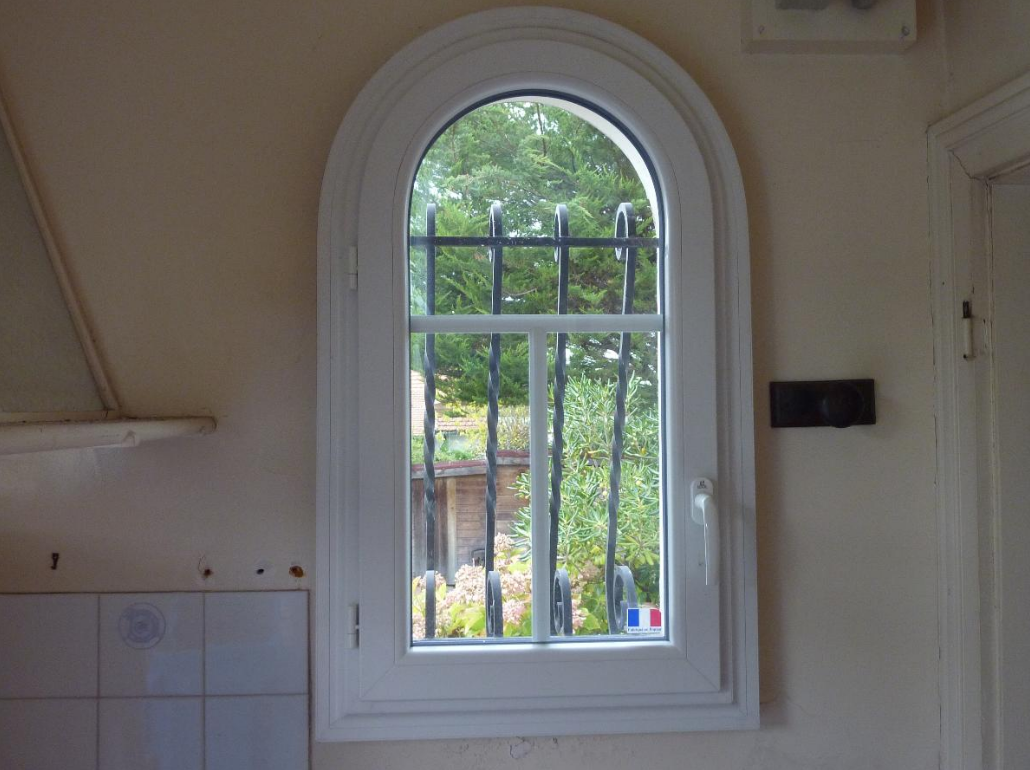 Une fenêtre en PVC donnant sur un jardin.