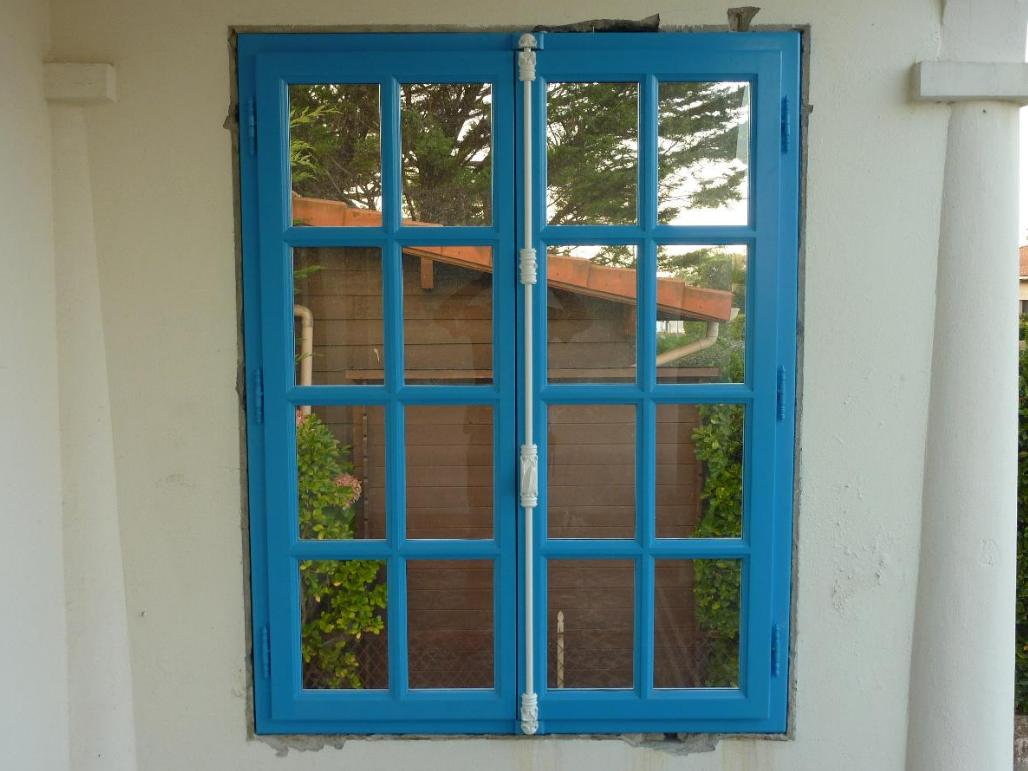 Une fenêtre en bois donnant sur un jardin.