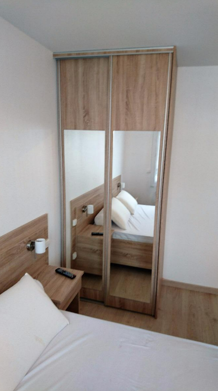 Un dressing en bois avec un miroir intégré, dans une chambre.