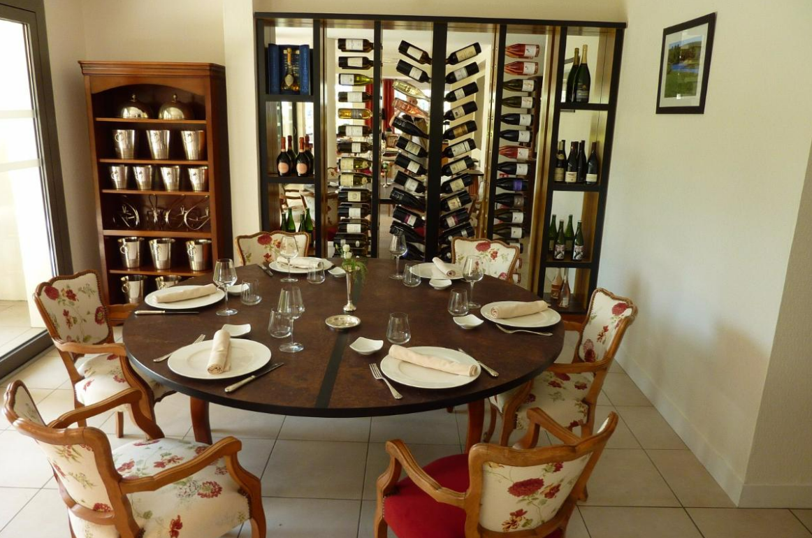 Une salle à manger avec une table ronde et un grand casier à bouteilles.