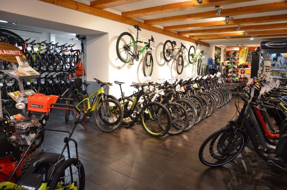 Innenraum eines Fahrradladens mit Reihen von Fahrrädern, darunter Mountainbikes und an der Wand befestigte Fahrräder.