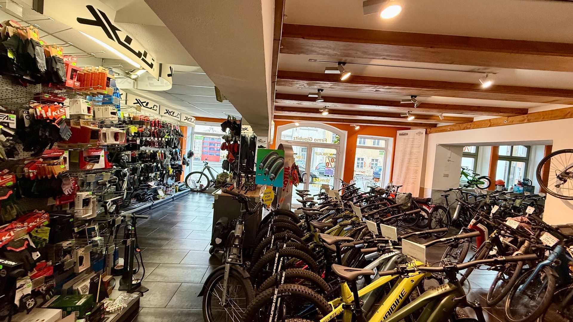 Schaufenster eines Fahrradladens mit Schwabe- und Simson-Schildern, Regalen mit Ersatzteilen und einem Ständer mit Broschüren und Werkzeugen
