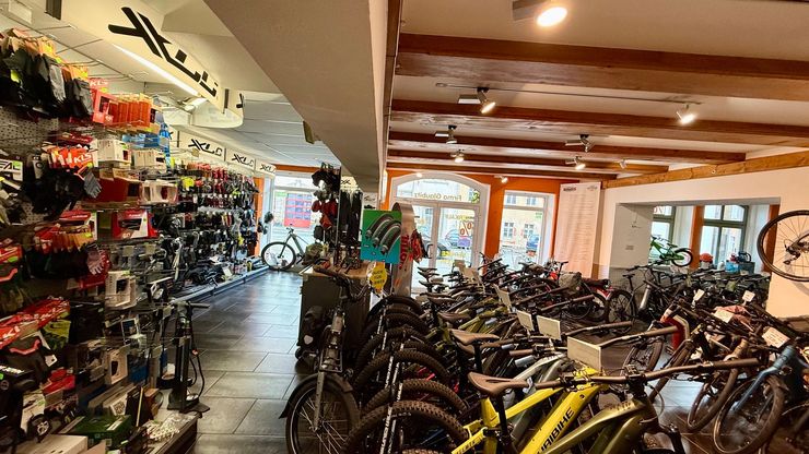 Schaufenster eines Fahrradladens mit Schwabe- und Simson-Schildern, Regalen mit Ersatzteilen und einem Ständer mit Broschüren und Werkzeugen