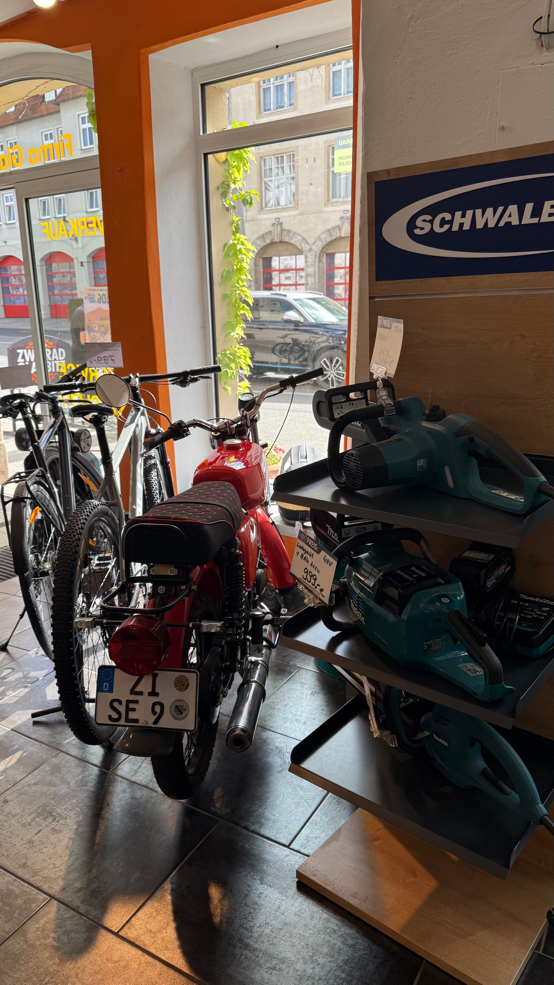 Innenansicht eines Fahrradgeschäfts mit Reihen von Fahrrädern, Helmen und Fahrradbekleidung in der Auslage.
