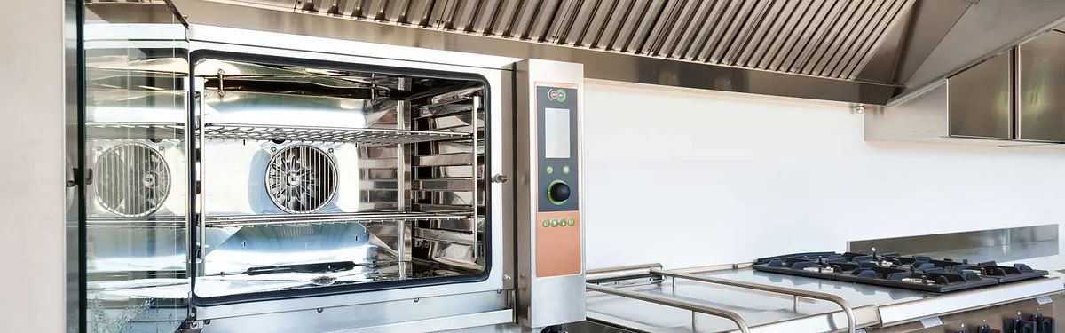 En una cocina hay un horno de acero inoxidable al lado de una estufa.