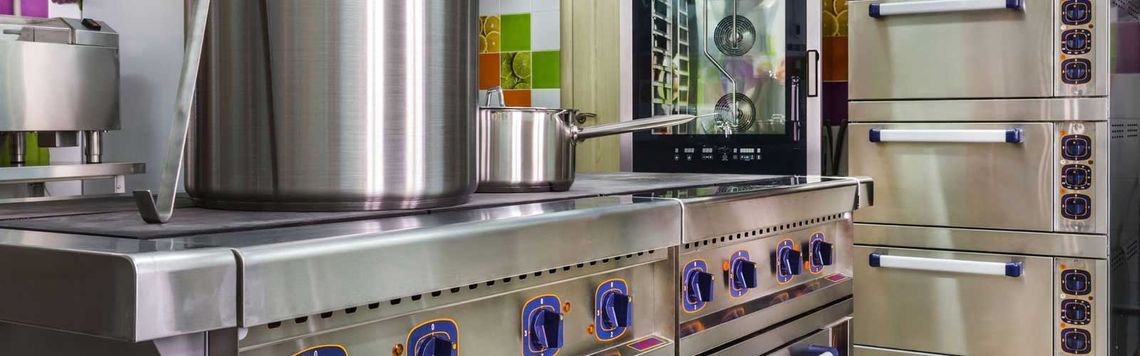 Una cocina con electrodomésticos de acero inoxidable y ollas en la estufa.