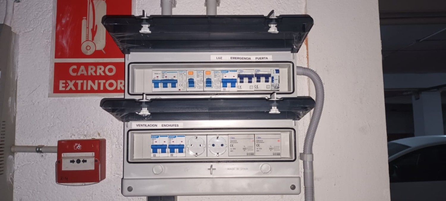 Cuadro de distribución eléctrica con disyuntores y tomas de corriente montado en una pared.