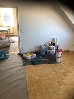 Ein Raum mit Holzboden und Farbeimern auf dem Boden.