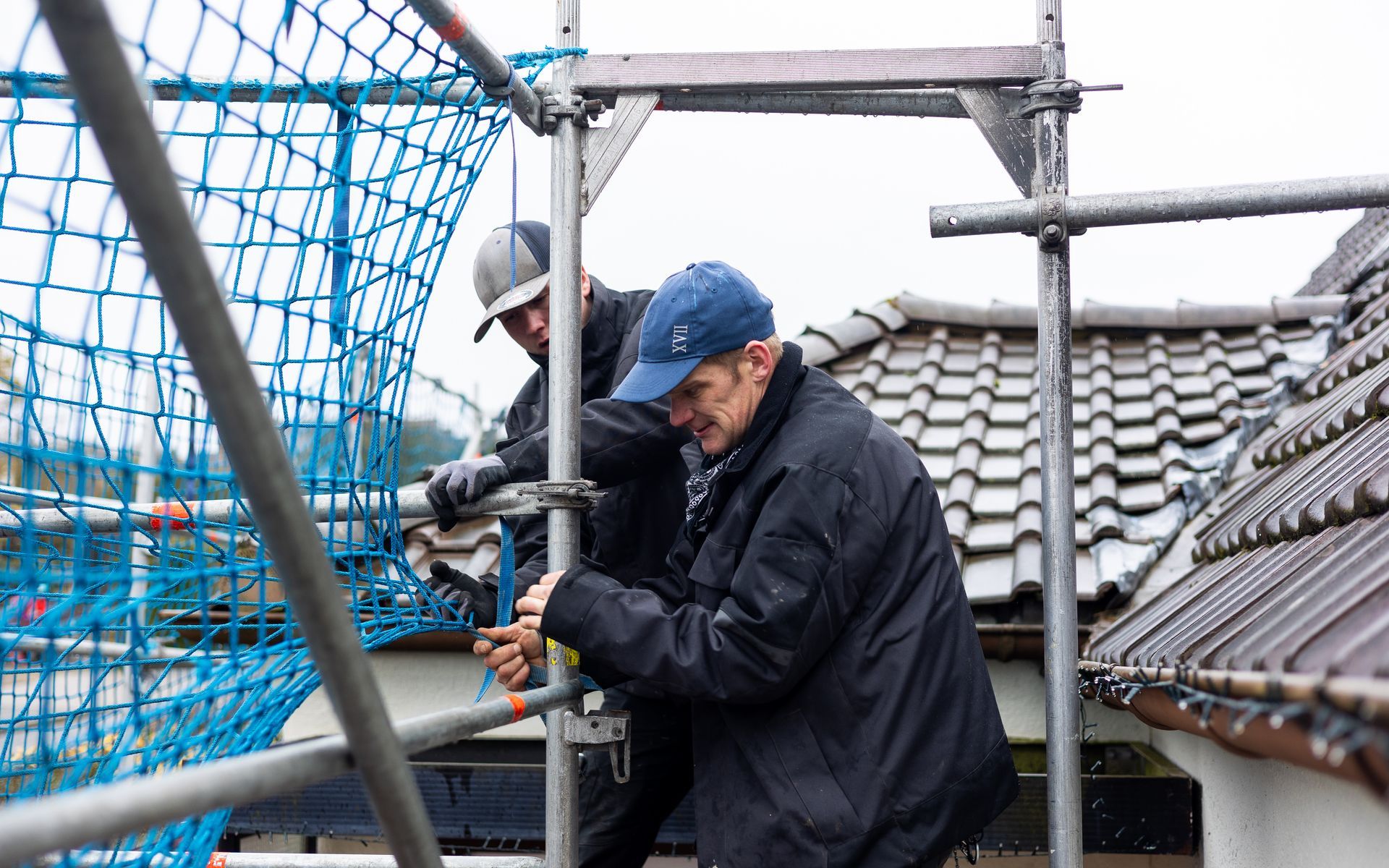 Zwei Männer arbeiten auf einem Gerüst auf einem Gebäude.