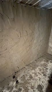 Ein schmutziger Raum mit einer Betonwand und einem Betonboden.