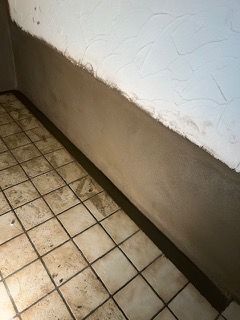 Ein Raum mit gefliestem Boden und weißer Wand.