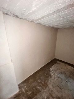 Ein leerer Raum mit Betonboden und weißer Wand.