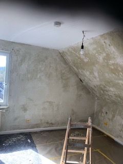 Ein Raum mit einer Leiter und einer Glühbirne, die von der Decke hängt.