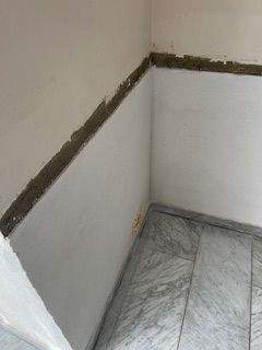 Eine Zimmerecke mit weißen Wänden und Marmorboden.