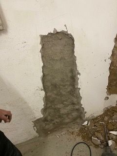 Eine Person steht neben einer Wand mit einem Loch darin.
