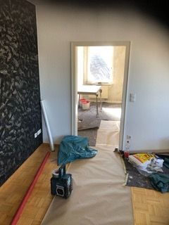 Ein Raum mit einer Tür, die zu einem Wohnzimmer führt, und einem Tisch.