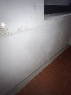 Eine weiße Wand mit einem Fenster und einem Ziegelboden in einem Raum.