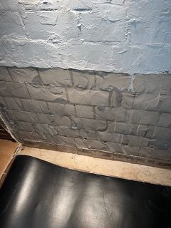 Eine Nahaufnahme einer Ziegelwand mit einer schwarzen Matte auf dem Boden.