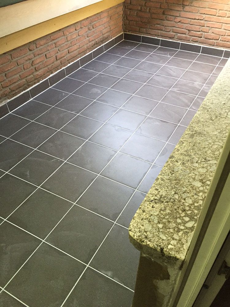 Ein Balkon mit gefliestem Boden und Ziegelwand.