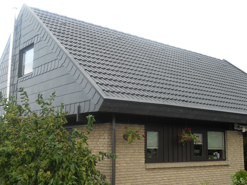 Ein Backsteinhaus mit einem grauen Dach und einem Baum davor