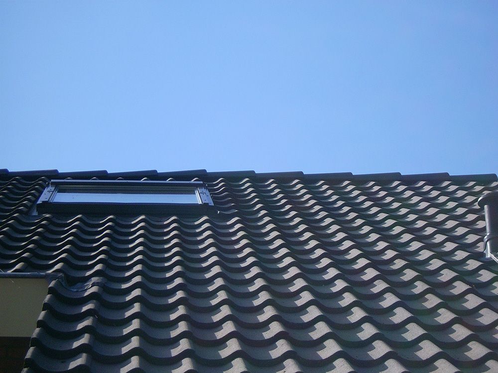 Ein Dach mit einem Oberlicht darauf und einem blauen Himmel im Hintergrund