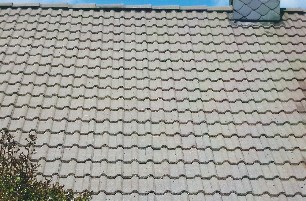 Ein Dach mit einem Schornstein darauf und einem blauen Himmel im Hintergrund.