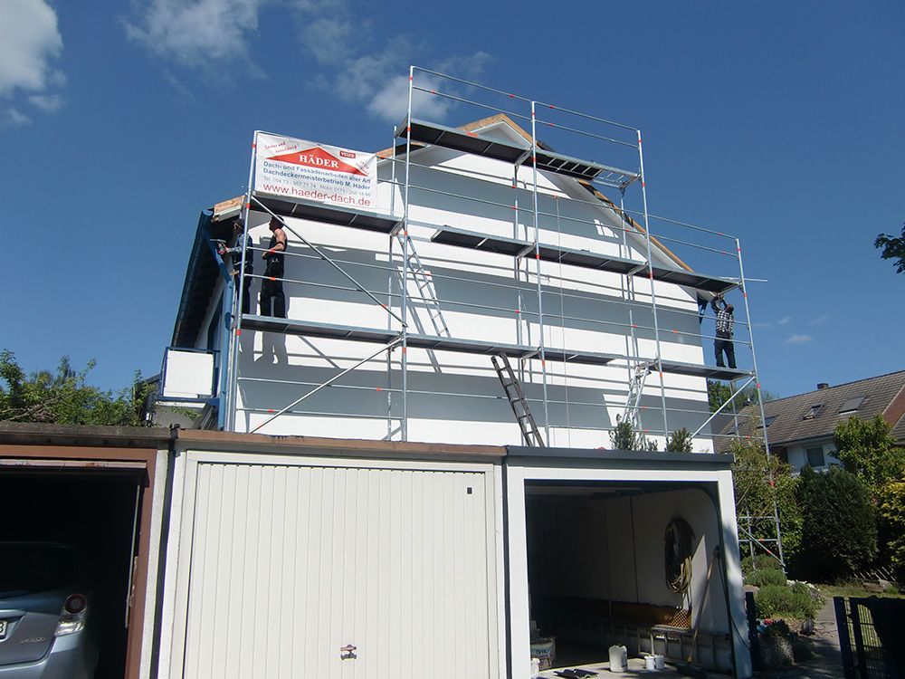 Ein Haus wird gestrichen, es ist von einem Gerüst umgeben.