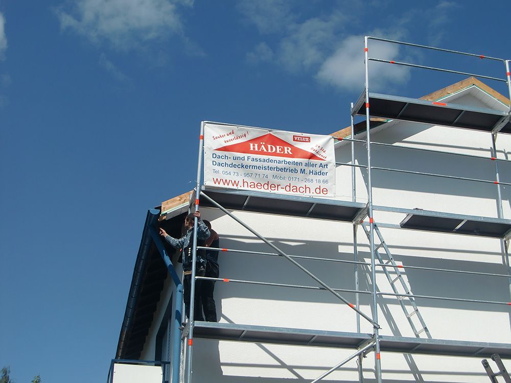 Ein Mann steht auf einem Gerüst neben einem Schild mit der Aufschrift „Bauer“