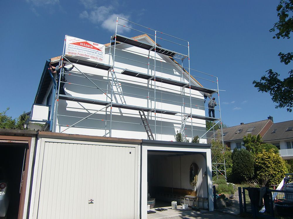 Ein Mann steht auf einem Gerüst an der Seite eines Hauses.