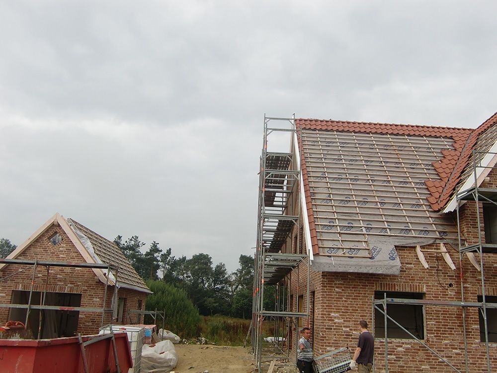 Ein Backsteinhaus mit einem roten Müllcontainer davor