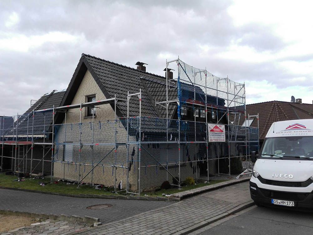 Ein weißer Lieferwagen parkt vor einem im Bau befindlichen Haus.