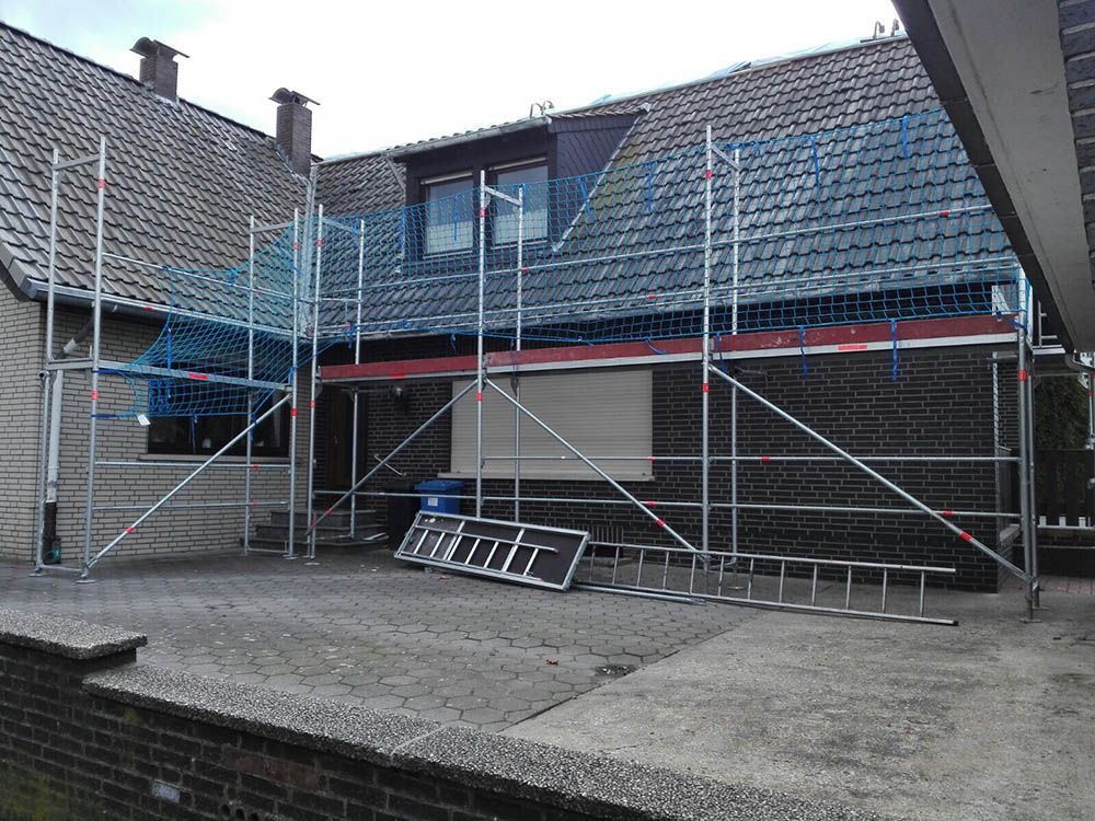 Ein Haus mit einem Gerüst und einer Leiter davor.