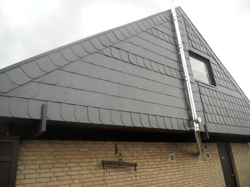 Ein Backsteingebäude mit einem grauen Dach und einem Fenster
