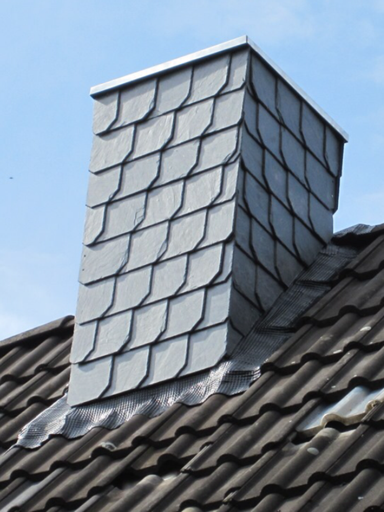 Ein Schornstein auf einem Ziegeldach mit einem blauen Himmel im Hintergrund