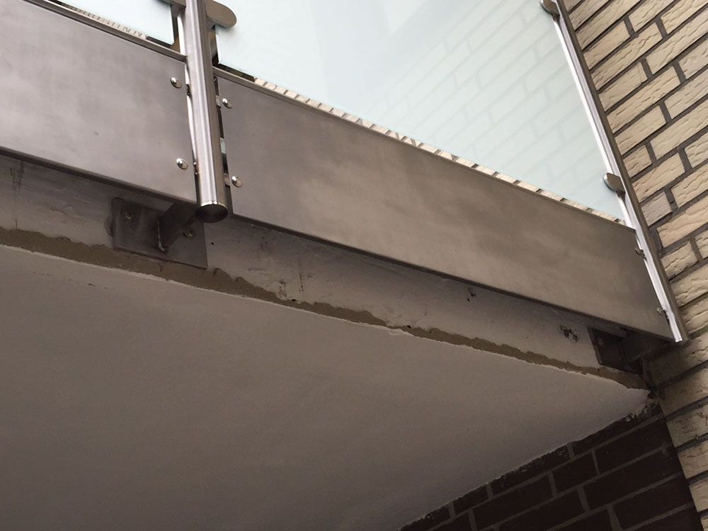 Ein Balkon mit einer Ziegelmauer und einem Geländer aus Edelstahl