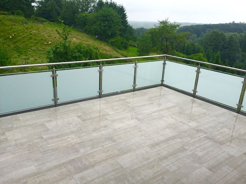 Ein Balkon mit Edelstahlgeländer und Blick auf einen Wald