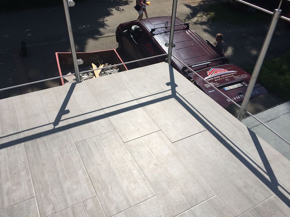 Ein Auto ist am Straßenrand neben einem Balkon geparkt.