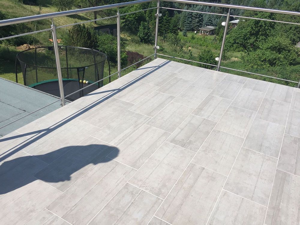 Ein Balkon mit einem Edelstahlgeländer und einem Trampolin im Hintergrund.
