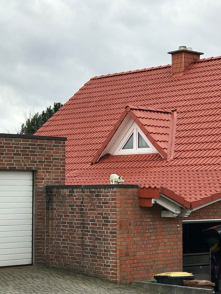 Ein Backsteinhaus mit rotem Dach und weißem Garagentor.