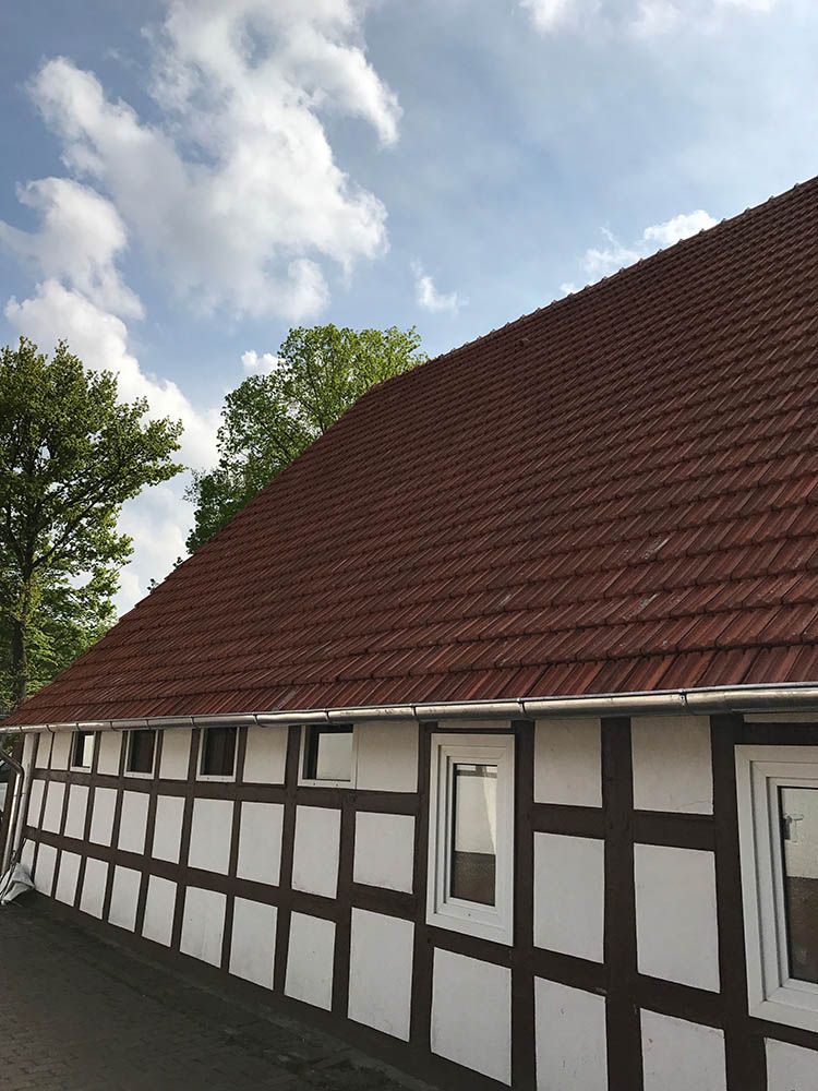 Ein weiß-braunes Haus mit einem roten Ziegeldach