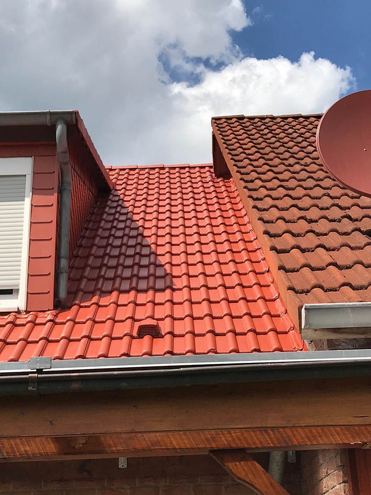 Ein rotes Ziegeldach mit einer Satellitenschüssel darauf.