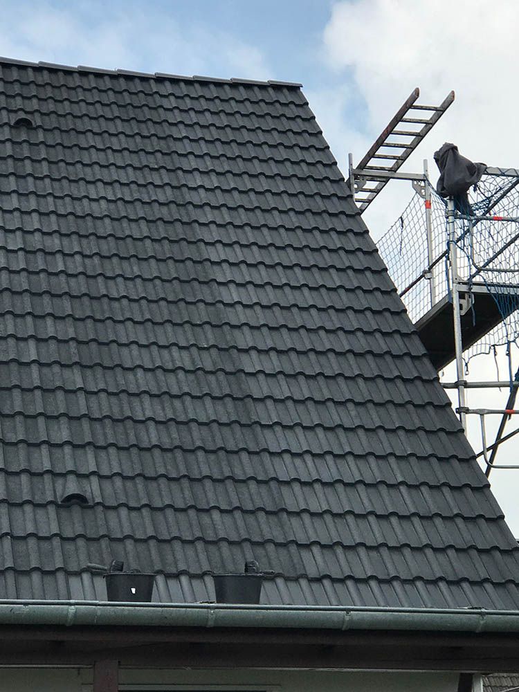 Ein schwarzes Ziegeldach mit einer Leiter darauf.