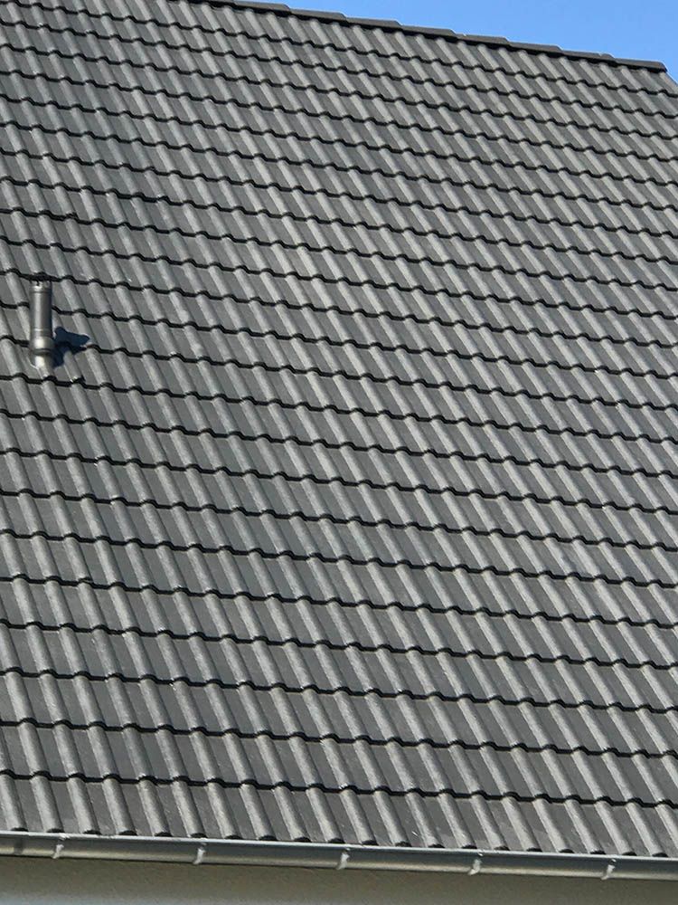 Eine Nahaufnahme eines grauen Ziegeldachs mit einem Oberlicht.