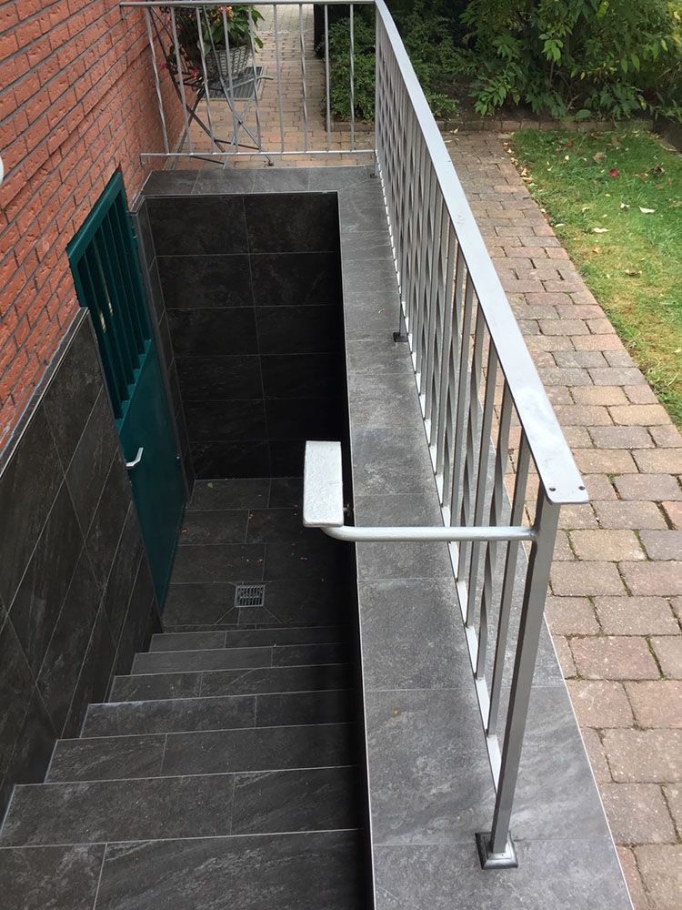 Eine Treppe mit einem Geländer aus Edelstahl, die in einen Keller führt.