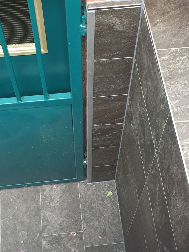 Eine blaue Tür ist neben einer schwarz gefliesten Wand