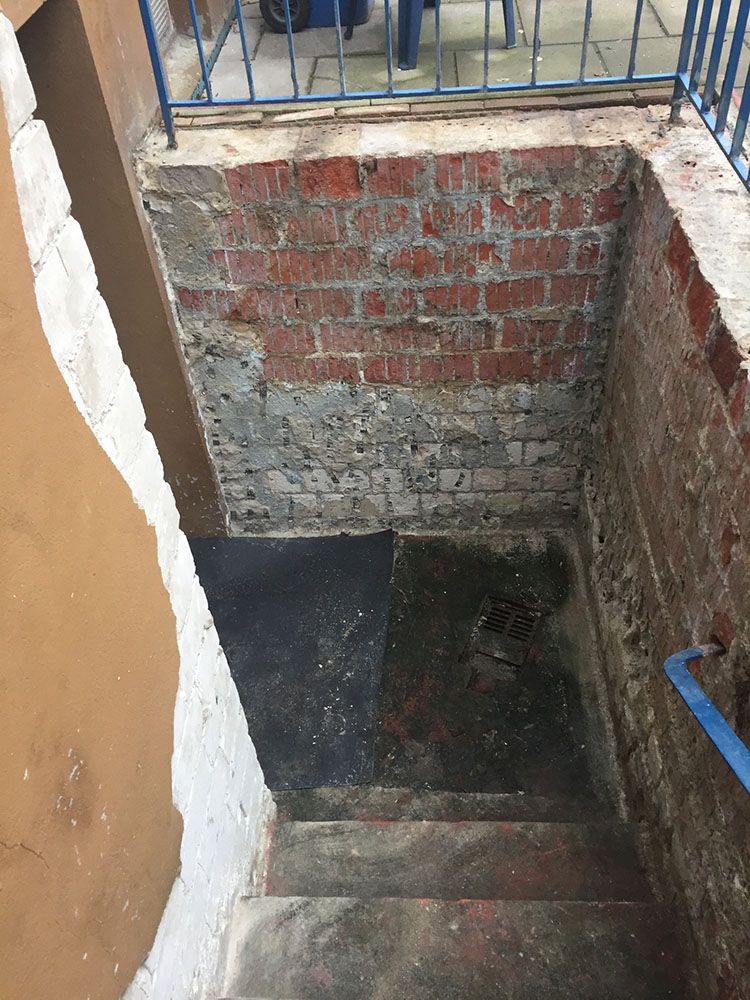 Eine Treppe, die zu einer Backsteinmauer hinaufführt.