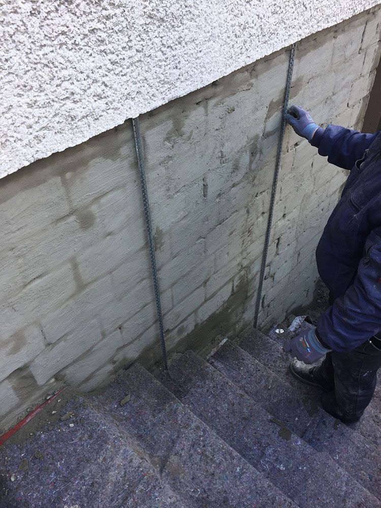 Eine Person steht auf einer Treppe neben einer Backsteinmauer.