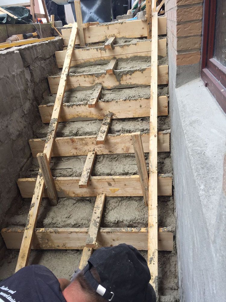 Ein Mann betoniert eine Holztreppe.