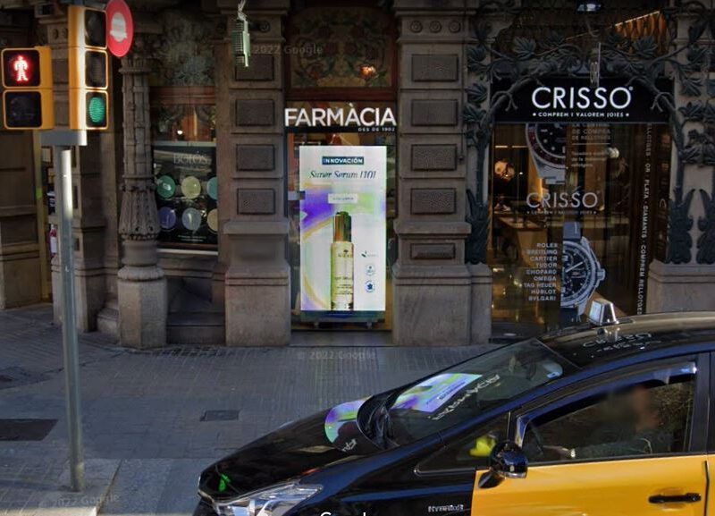 Un coche negro está aparcado delante de una farmacia.