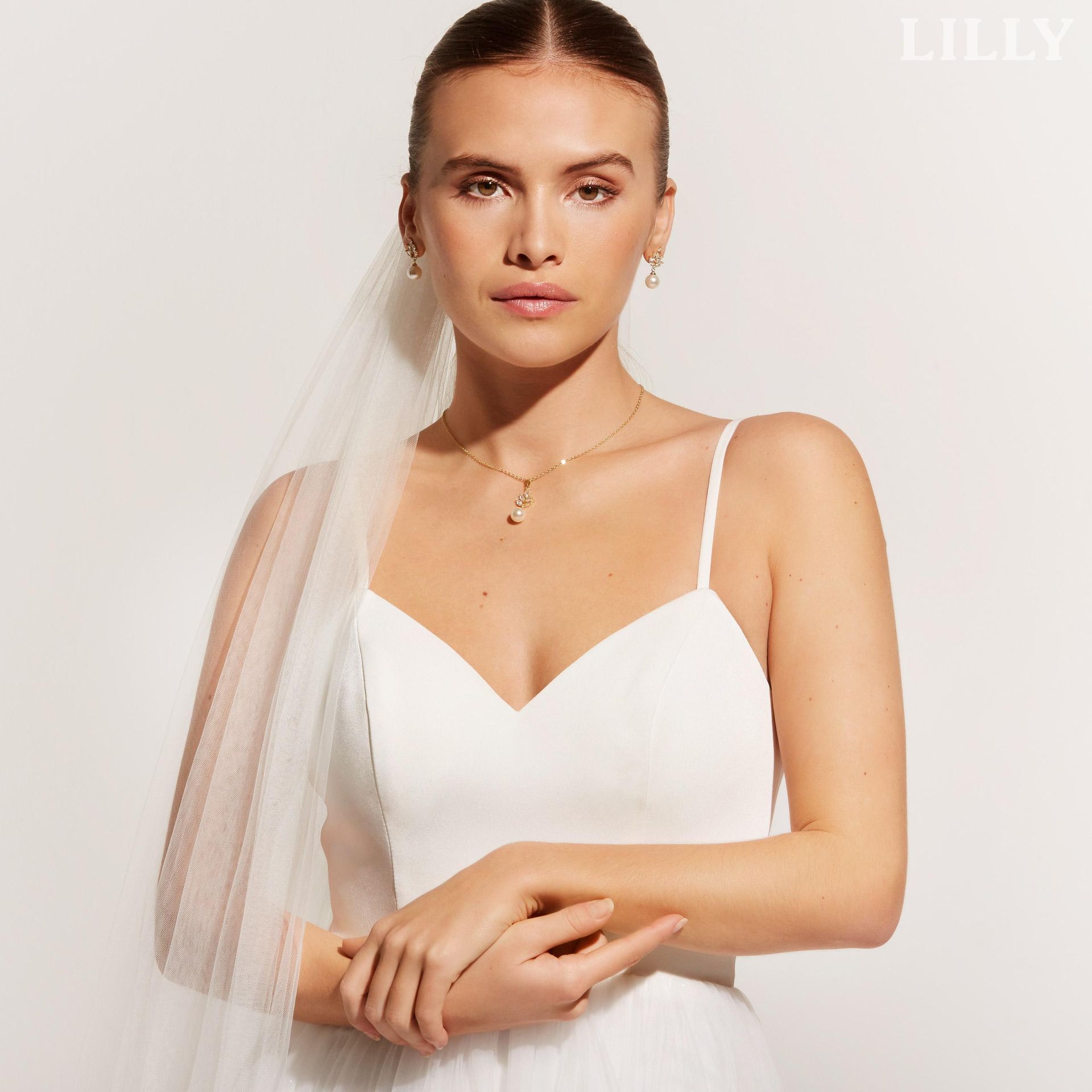 Eine Frau in einem weißen Kleid steht vor Blumen.